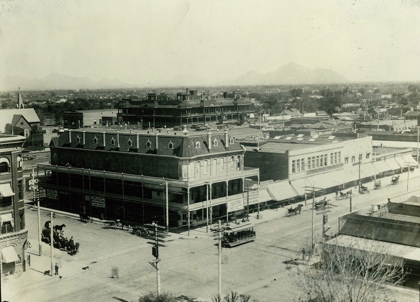 A 1900s photograph of a Phoenix street, featuring a streetcar and several horses. Camelback Mountain in the distance