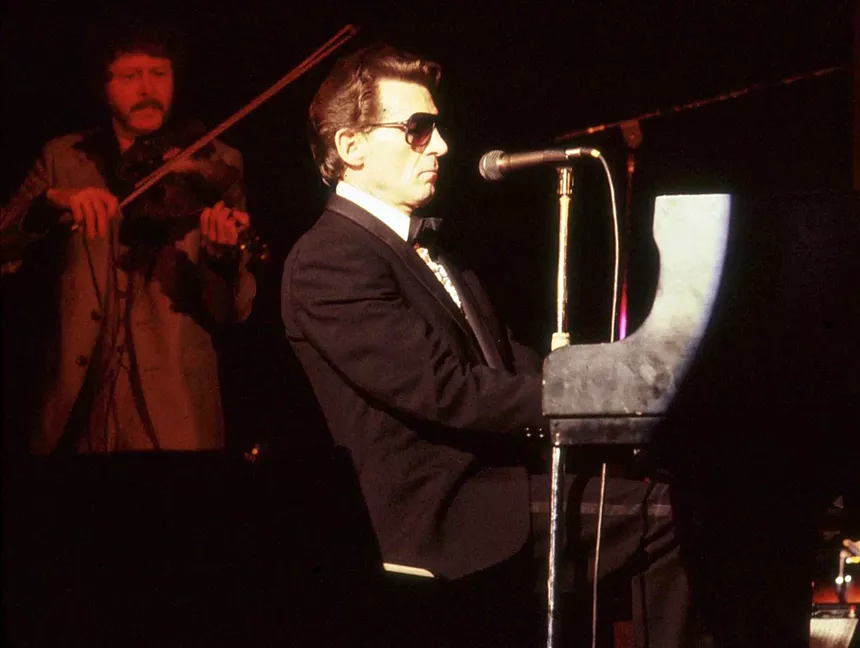 A country music singer sitting at a piano onstage.