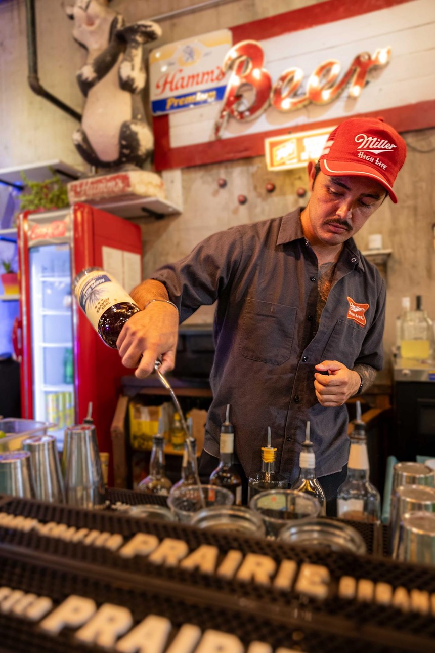 A man making drinks behind a bar.