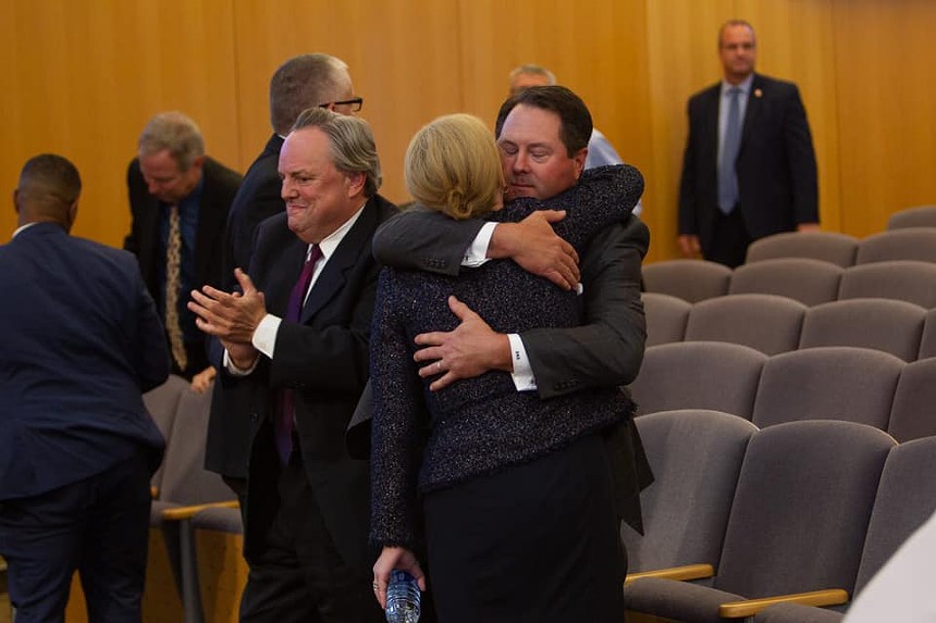 Two people embrace in a courtroom