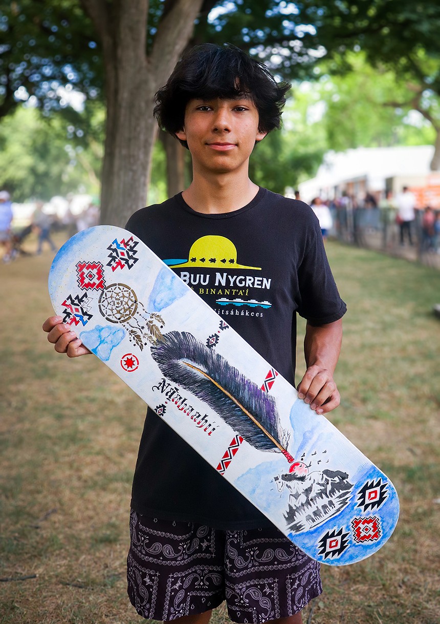 A young boy holding a skateboard.