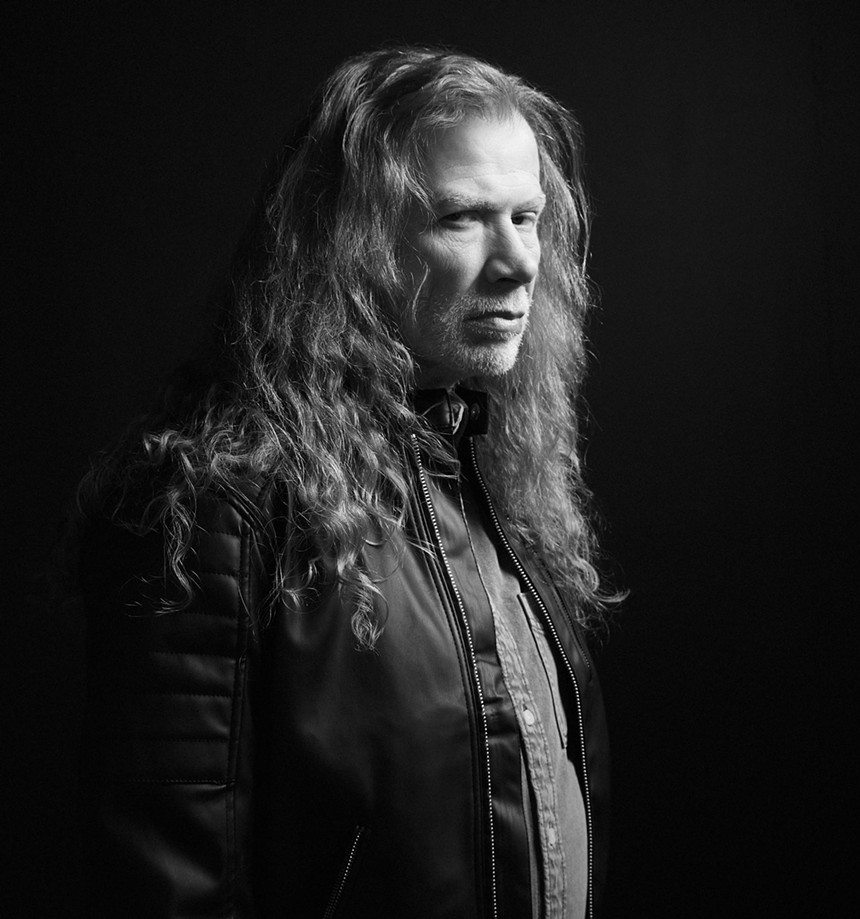 A black and white portrait of an older man with long hair.