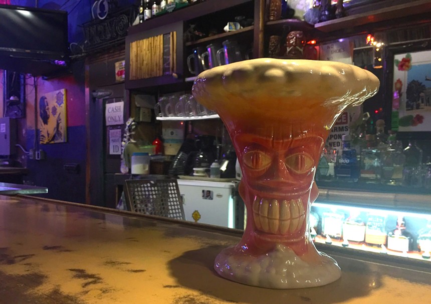 A tiki drink sitting on a bar.