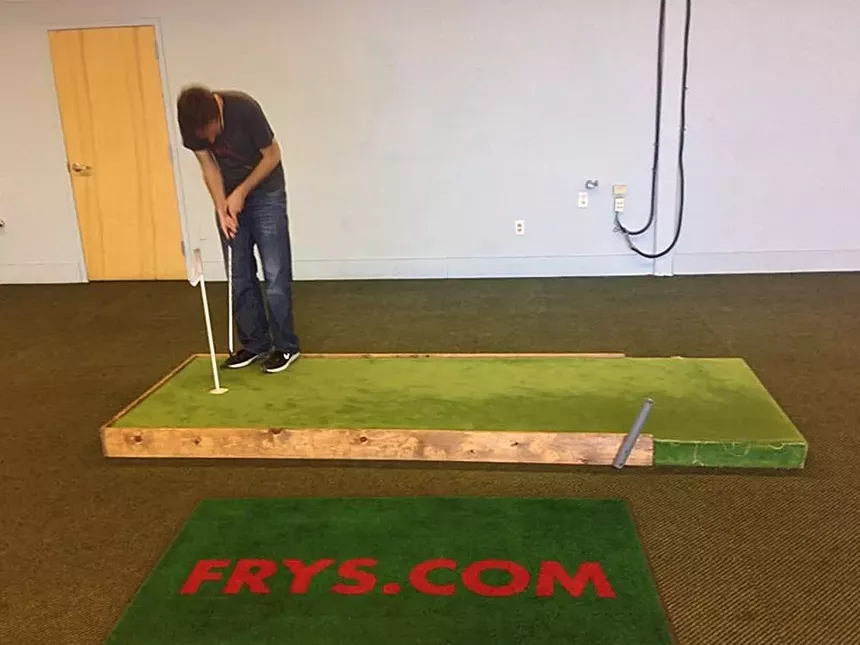 A person puts on a small putting green.