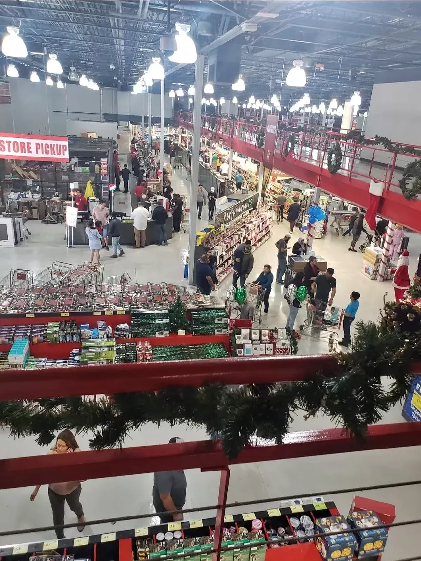 A crowd of people on the sales floor of an electronics store.