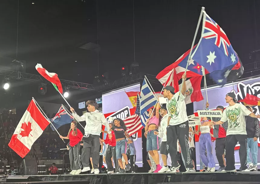 People on a stage holding the flags of various countries.