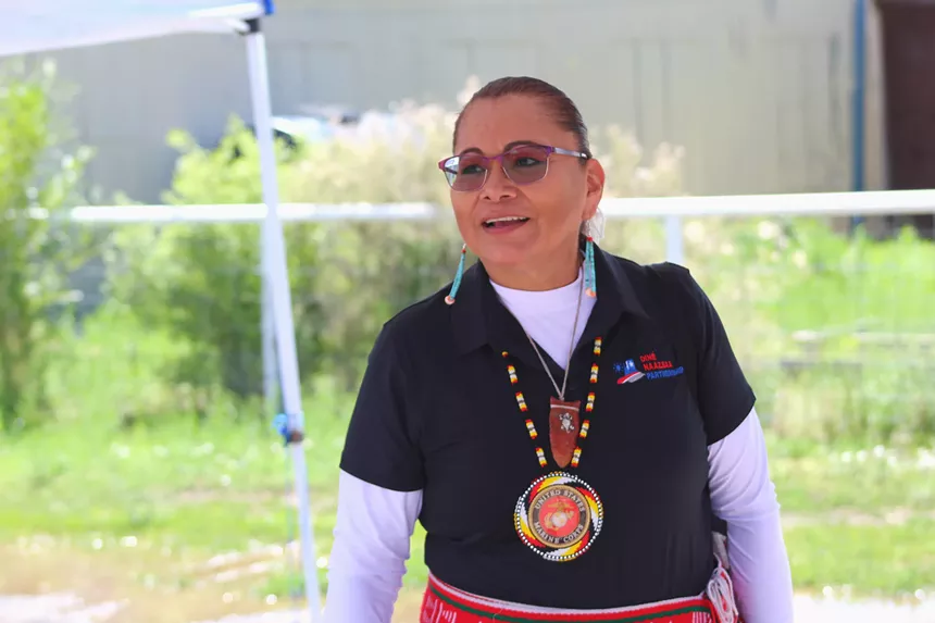 A woman in glasses smiles while speaking.