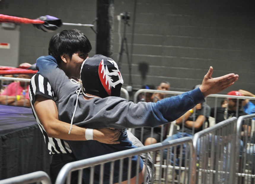 A referee carrying a professional wrestler in his arms.