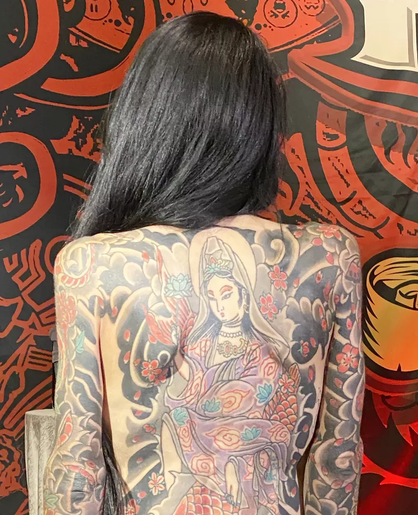 A woman displaying a large tattoo on her back.