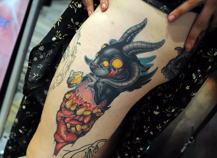 A tattoo of a creatue on a person's leg.
