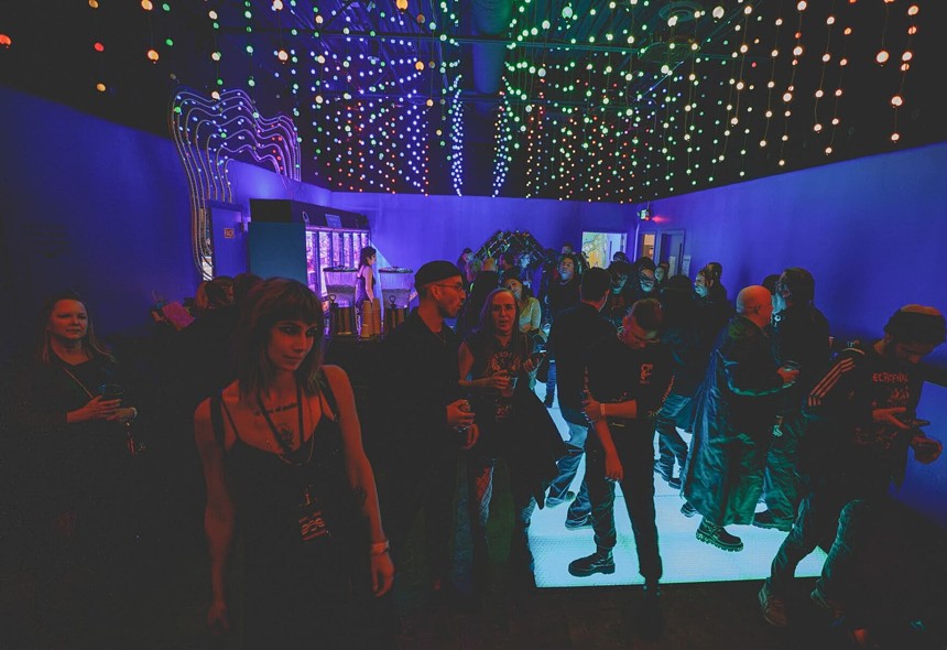 A crowd of people standing around in a darkened room.