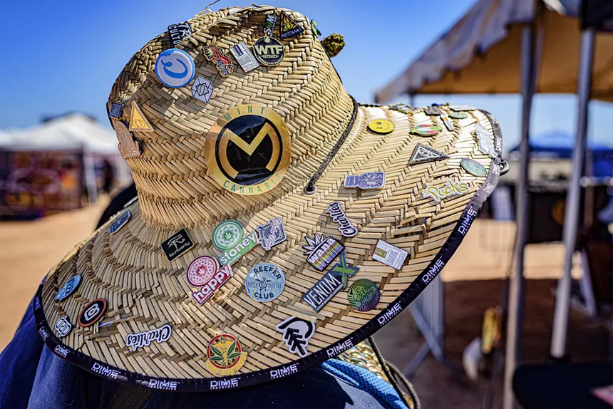 a straw hat covered with weed company pins