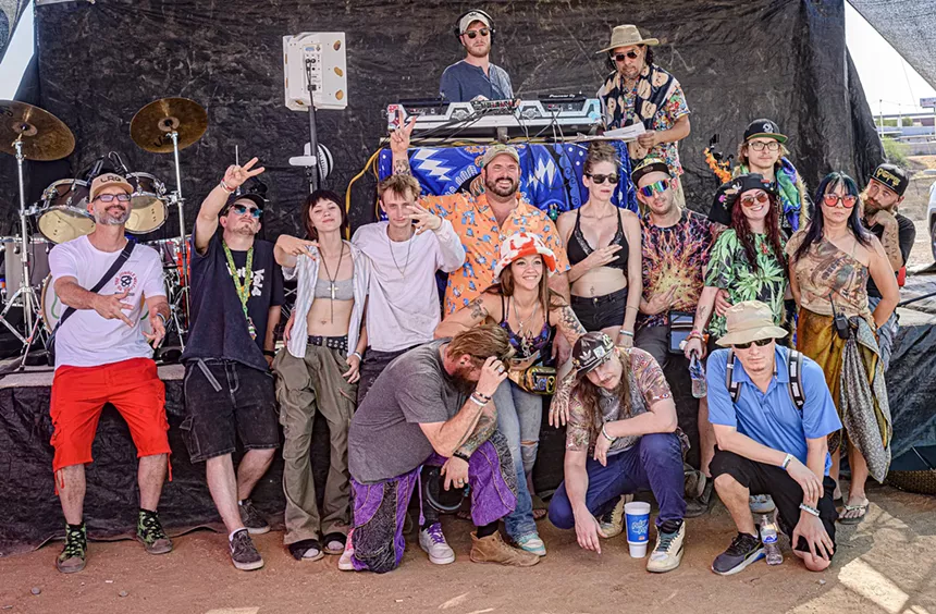 A group of people pose for photos in front of a stage featuring a drum set and other instruments