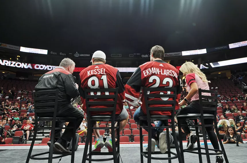 men in arizona coyotes jerseys sit with their back to the viewer