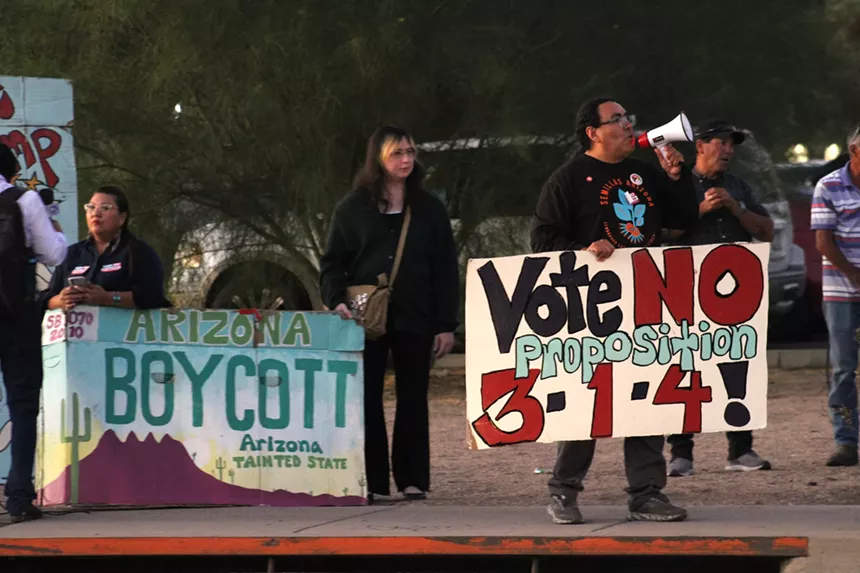 protesters along a road with a sign that reads "Vote No Proposition 314!"