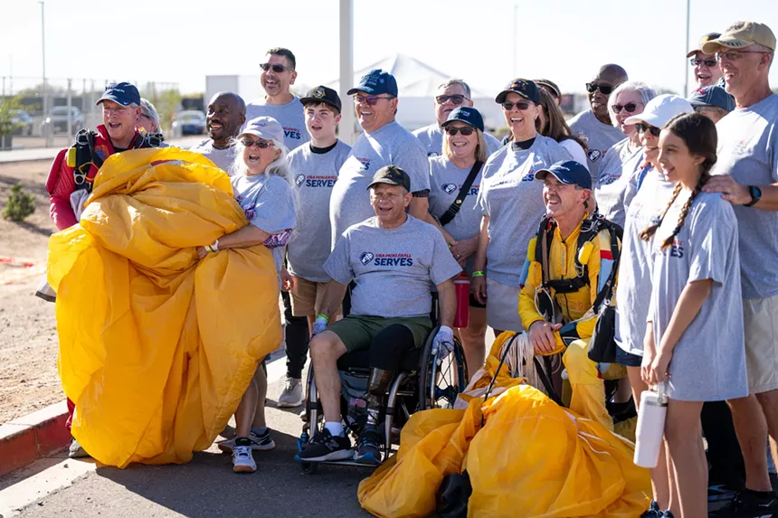 two skydivers pose for a photo with a group of people