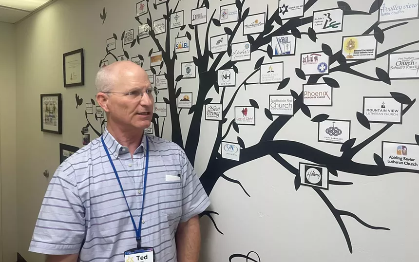 a man in a polo in front of a tree mural