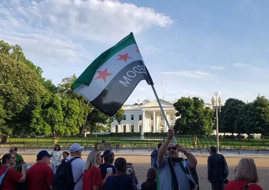 a man waves a syrian opposition flag in front of the white house