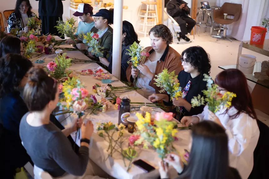 People working on flower arrangements at a table.