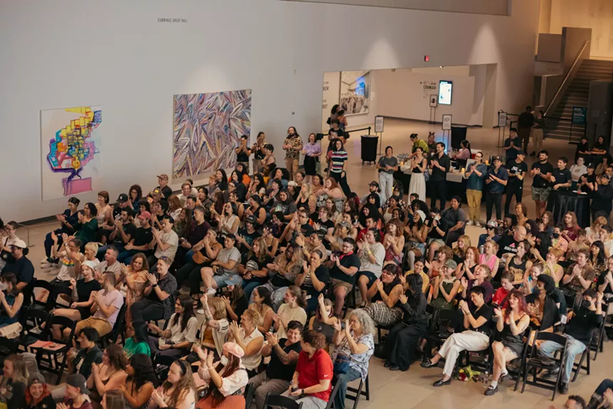 An audience of people at an art museum.