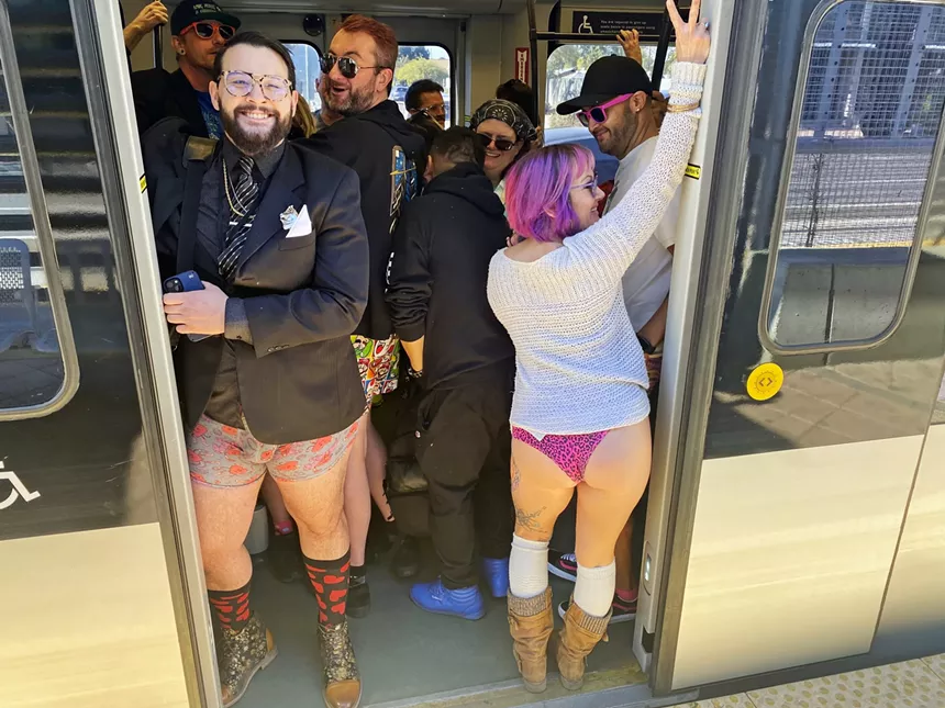 People wearing no pants on a train.
