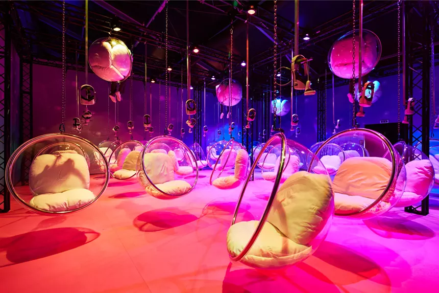 A pink room full of hanging chairs.