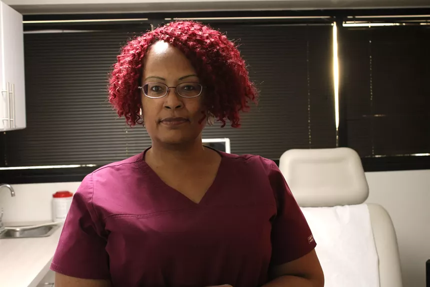 an african-american woman in purple scrubs in an exam room