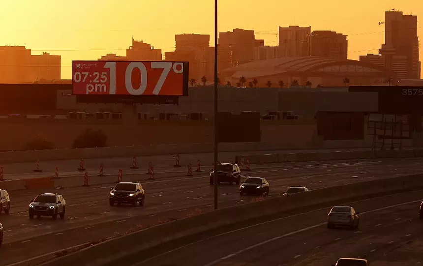 a phoenix highway with a billboard reading 107 degrees at 7:25 p.m.