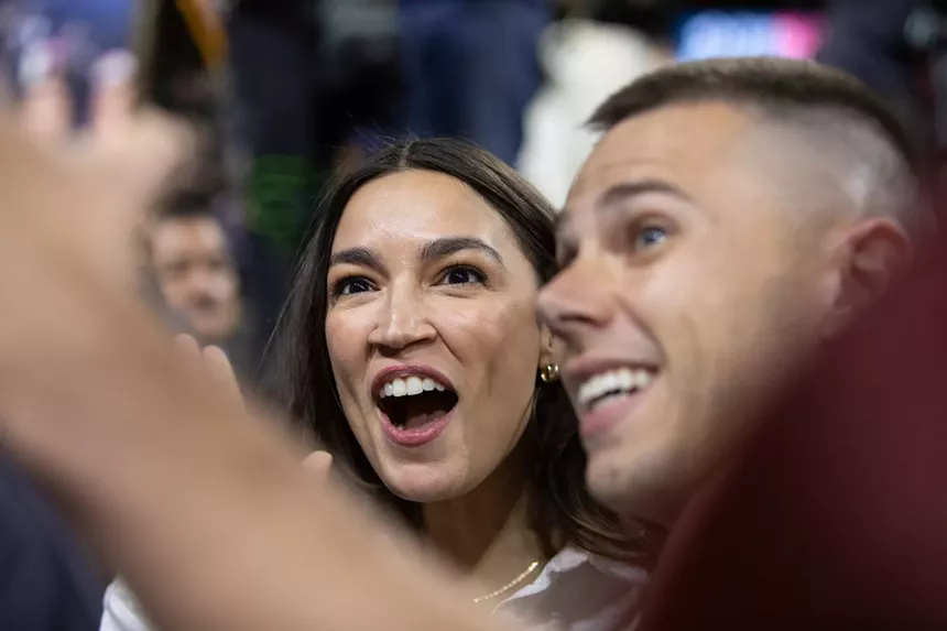 alexandria ocasio-cortez poses for a selfie with a fan