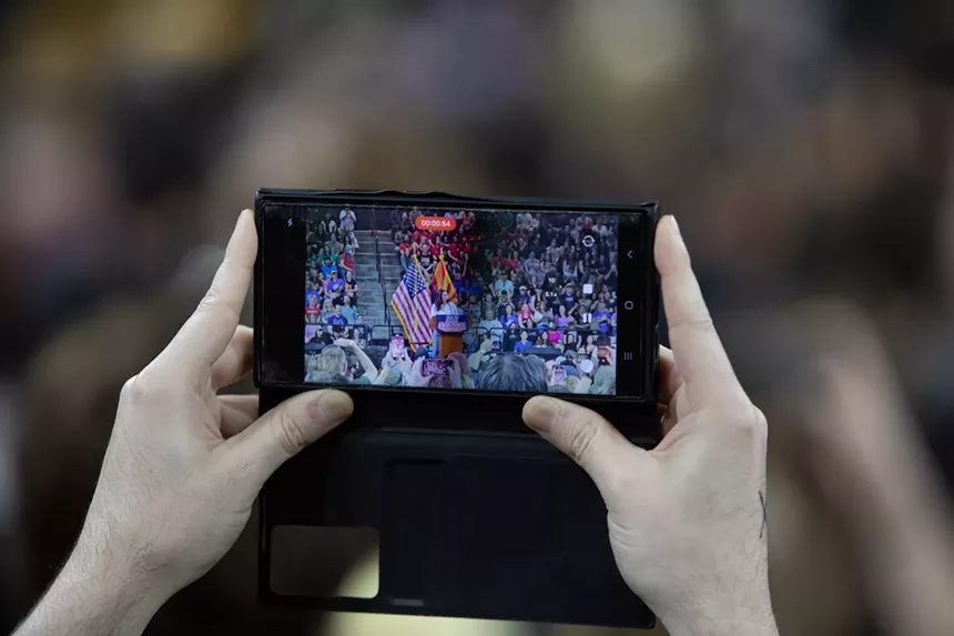 a person taking a photo with their phone of a rally