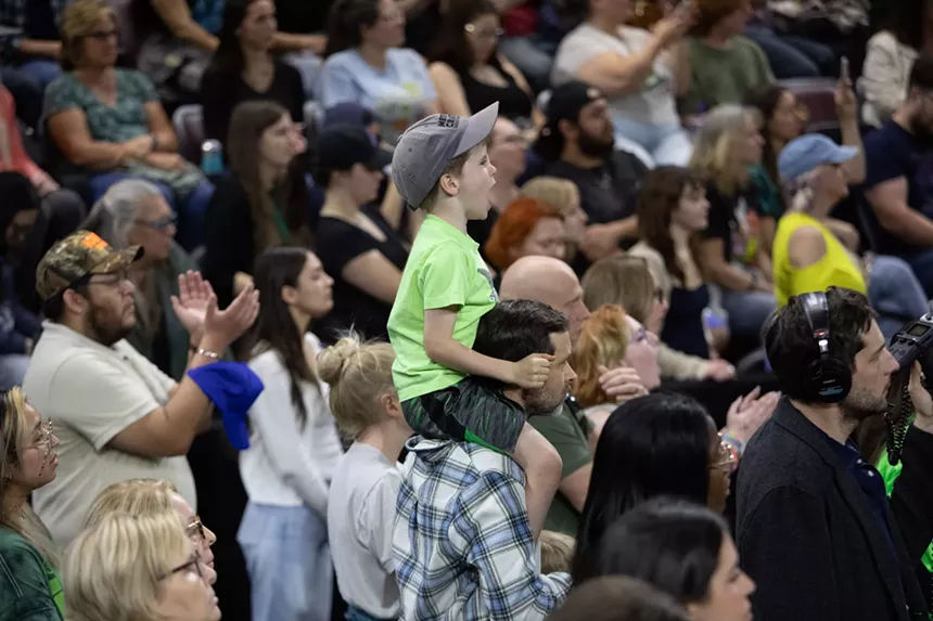 a young boy sits on his dad's shoulders at a rally