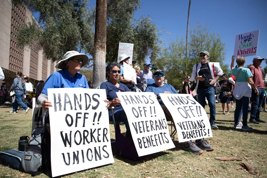protesters hold "hands off" signs