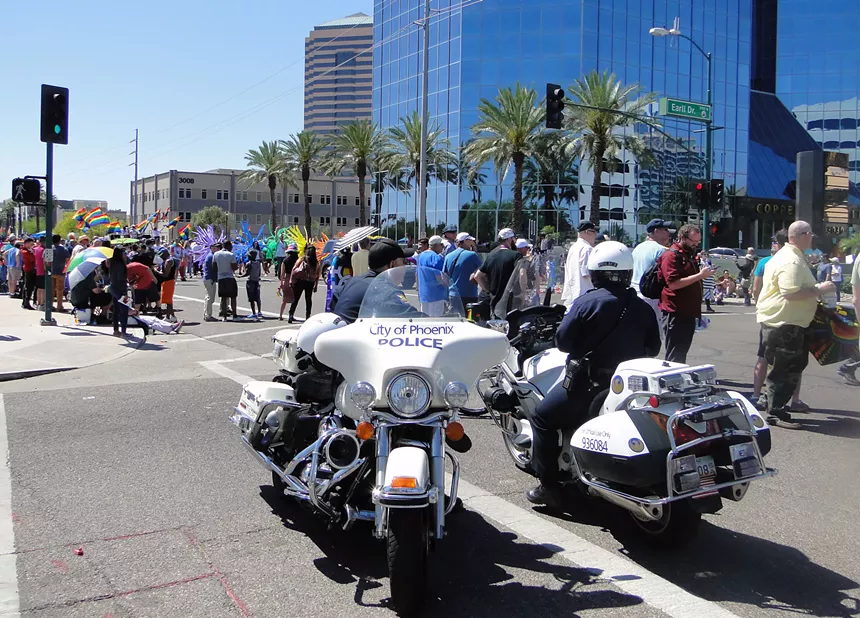 police officers on motorcycles watch a pride parade