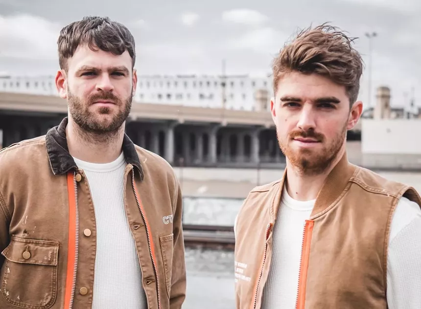 Two men stand in front of a building