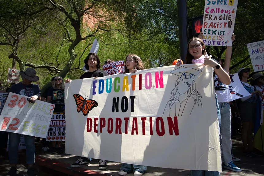 three people hold a banner that says "education not deportation"