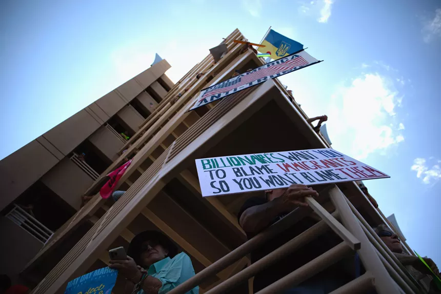 protesters hang signs over the railings of a parking garage