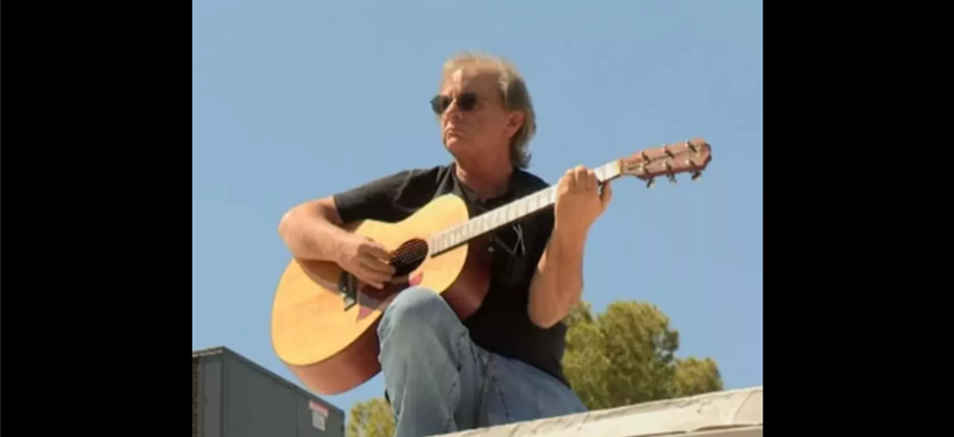 a man sits with a guitar
