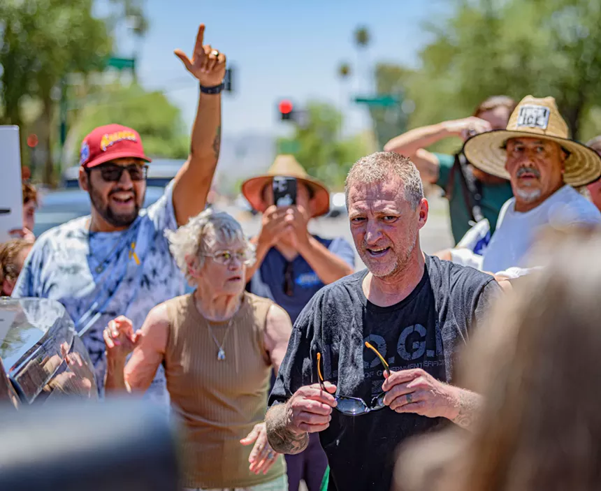 A man in a DOGE shirt stands among protesters