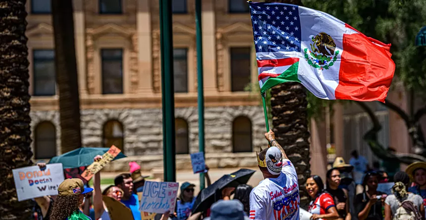 a protester waves a combined U.S. and Mexico flag
