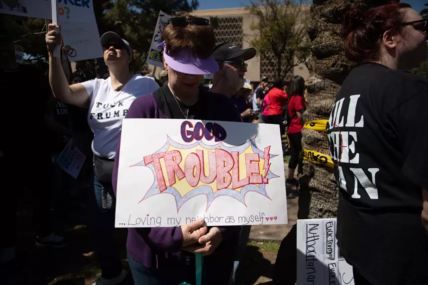 a protester with a sign that says "good trouble: loving my neighbor as myself"