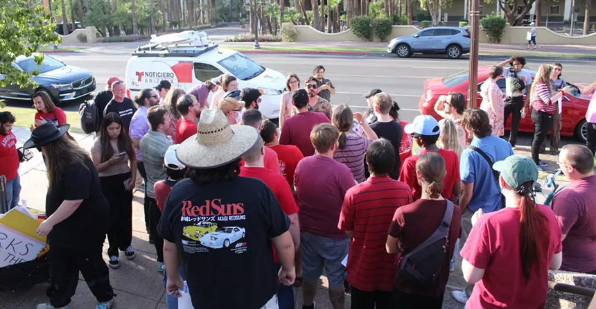a man speaks to a crowd of people on the sidewalk