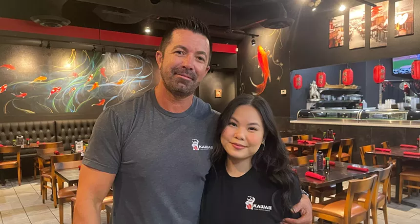 a man and woman pose for a photo in a restaurant