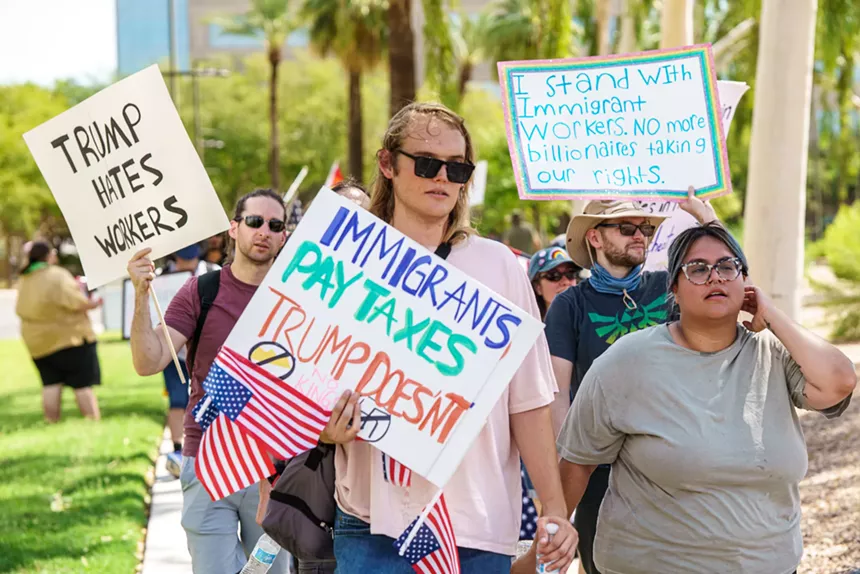 protesters with signs that say "trump hates workers" and "immigrants pay taxes, trump doesn't"