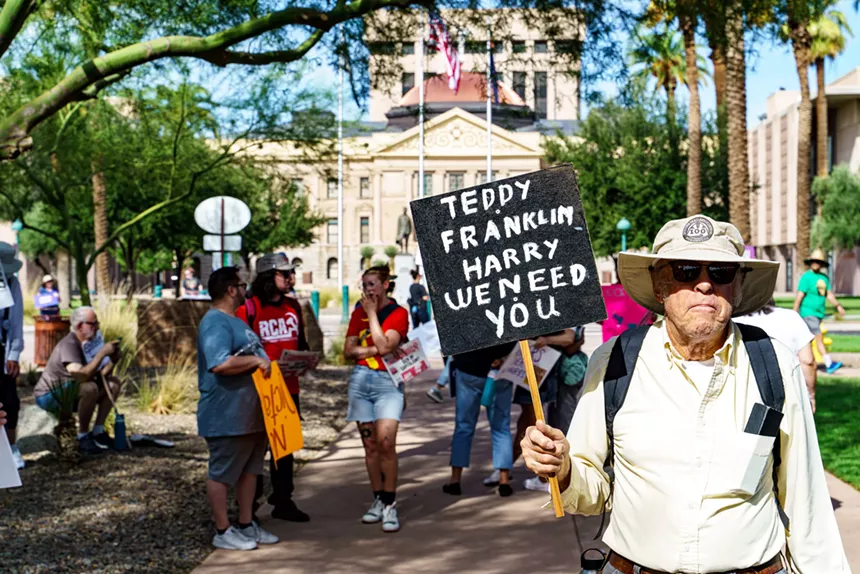 a protester holds a sign that says "teddy, franklin, harry, we need you"
