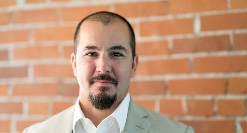a man in a tan suit with a mustache and goatee