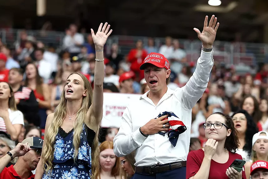 people in maga hats pray in a crowd