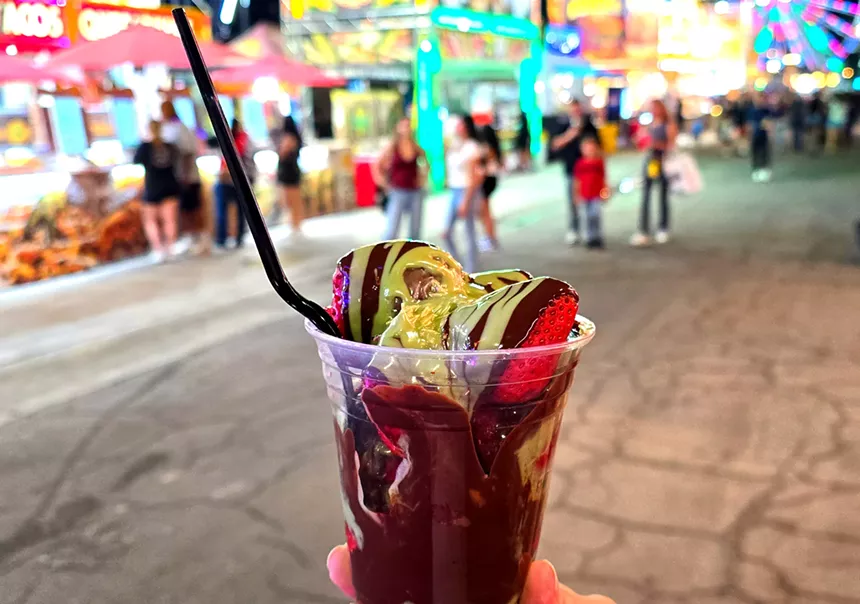 a cup of strawberries covered in chocolate and pistachio sauce