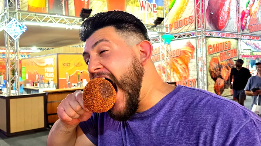 a man biting into a candied apple covered in tajin