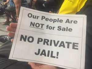 Opponents quietly waved signs after Mayor John Giles threatened to have police remove anyone who caused a "disturbance" during the meeting. - ANTONIA FARZAN