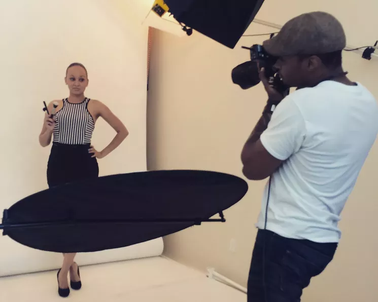Jalia poses in a racerback body con dress with a black skirt and skinny black belt worn on top. - ROMEN COLE